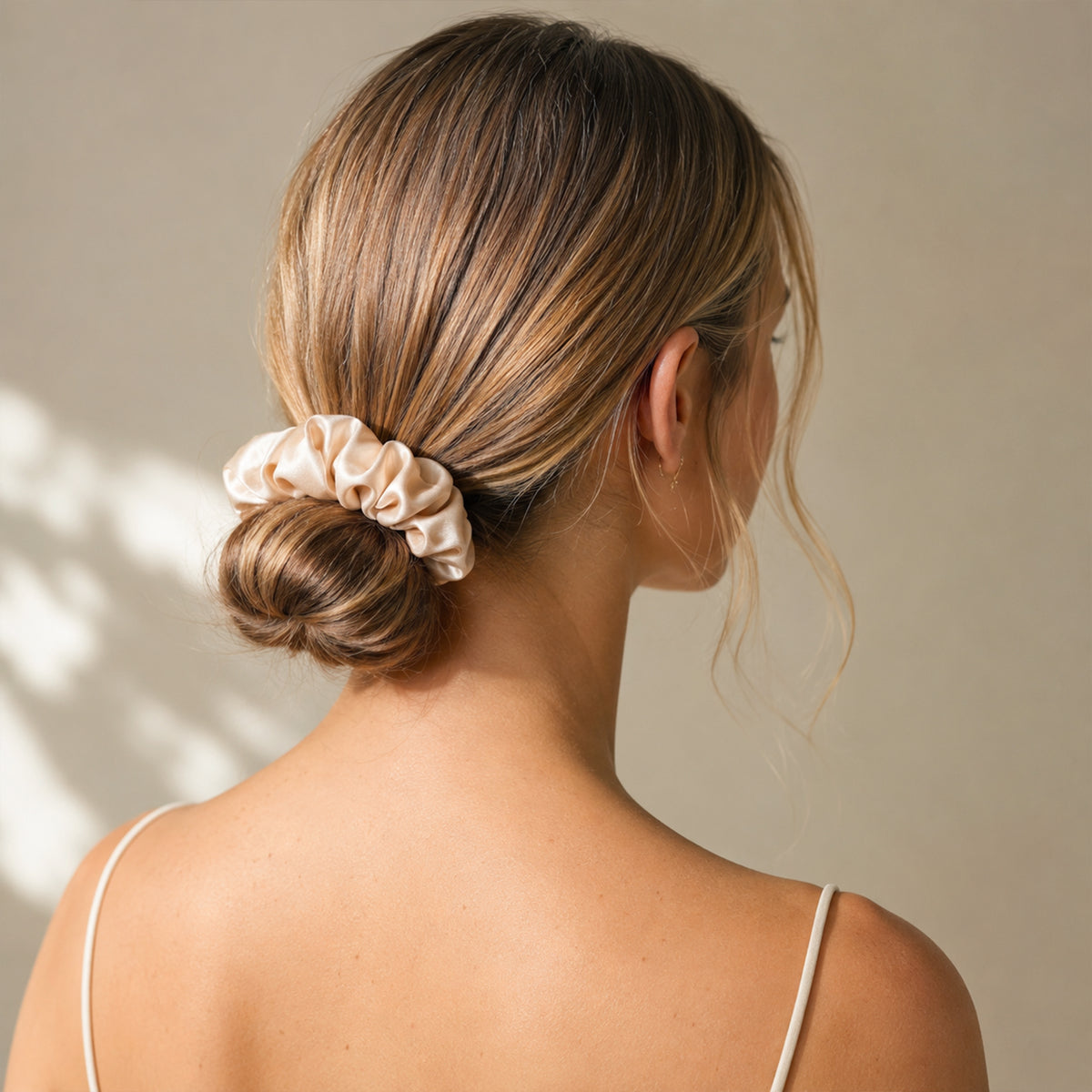 Low bun held by a large cream Silk Scrunchie, back view