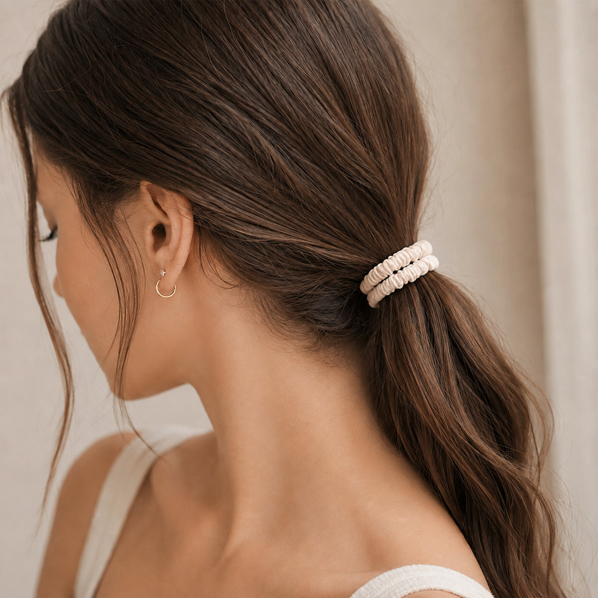 Close-up of a ponytail held by two stacked cream skinny Silk Scrunchies